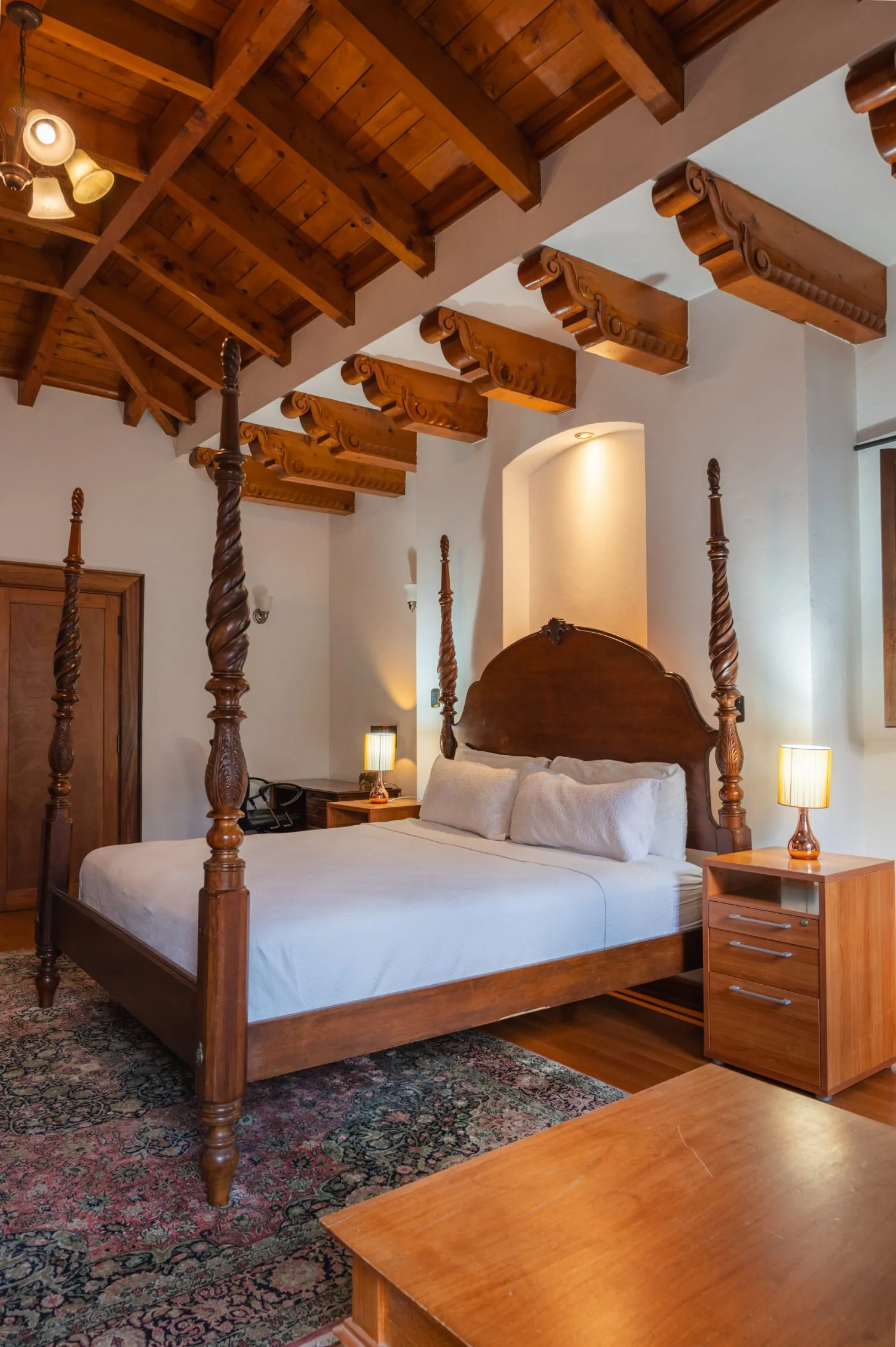 Suite con cama de dosel bajo vigas talladas
