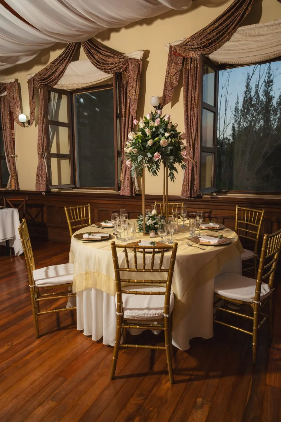 Salón montado con mesas redondas y centros de rosas