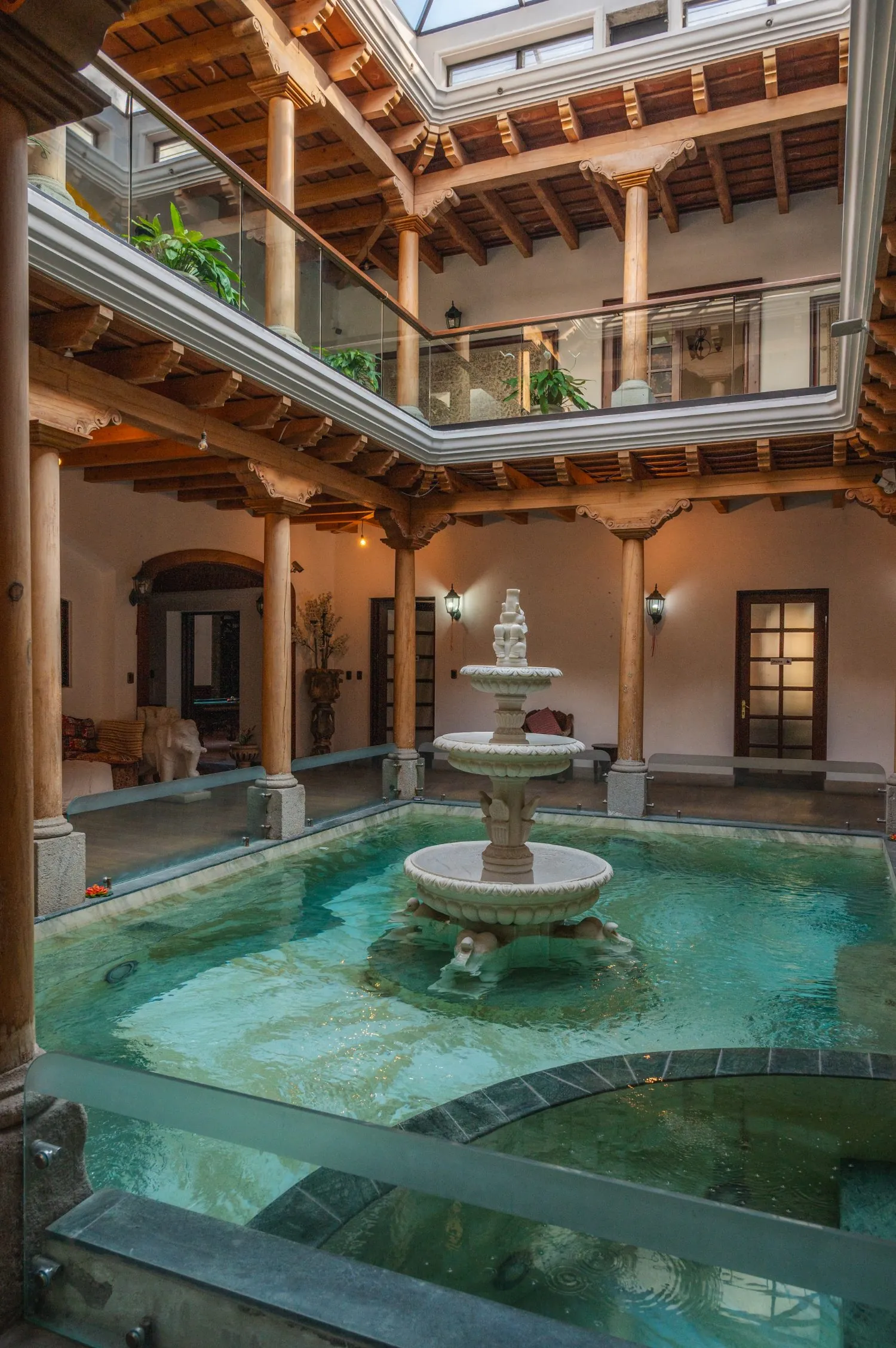 Patio interior con piscina, fuente de mármol y columnas de madera